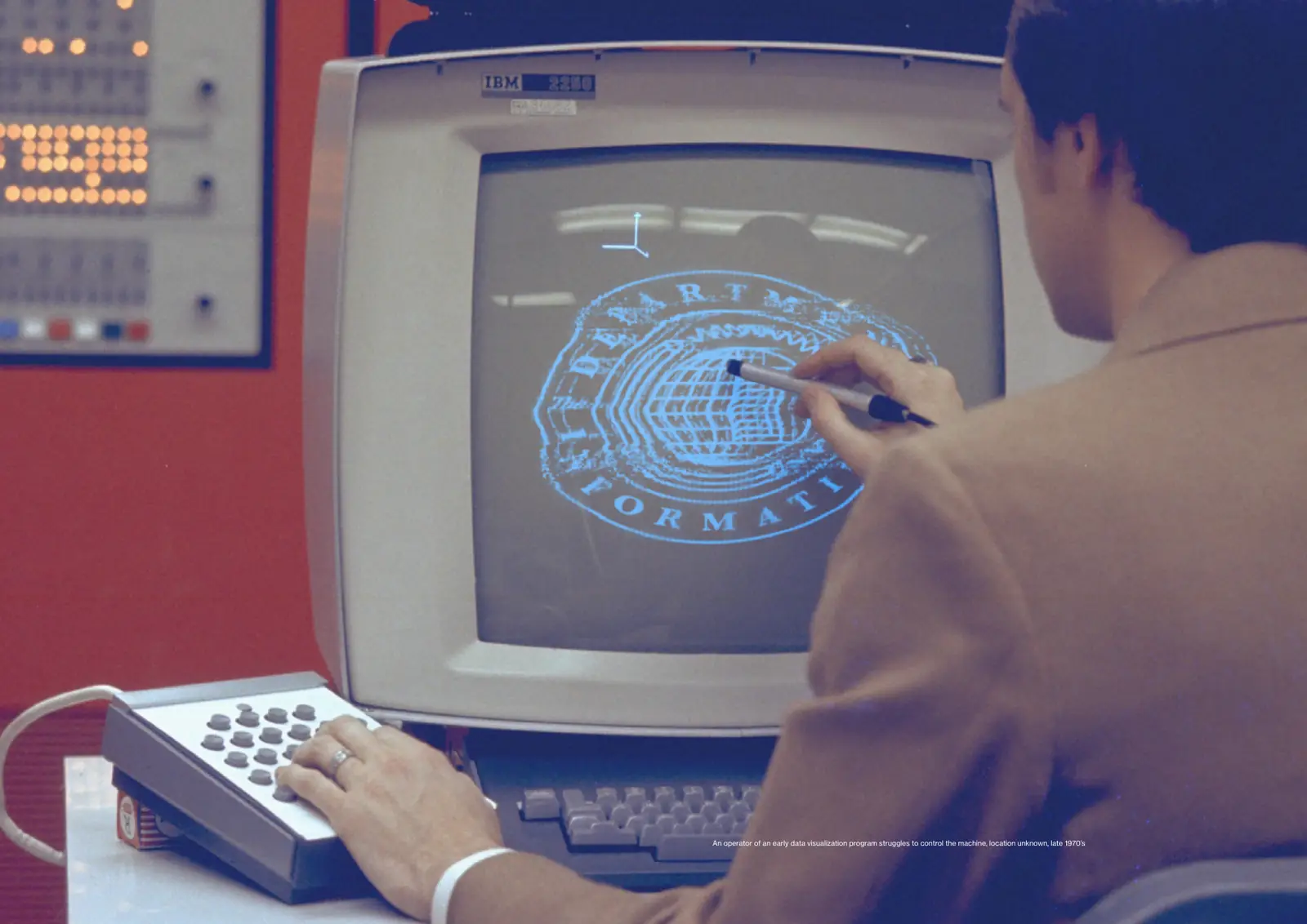 Color photograph of an operator using a light pen on an IBM 2250 display showing a distorted Department seal.